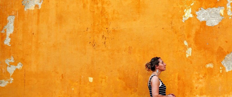 a woman in front of an orange wall